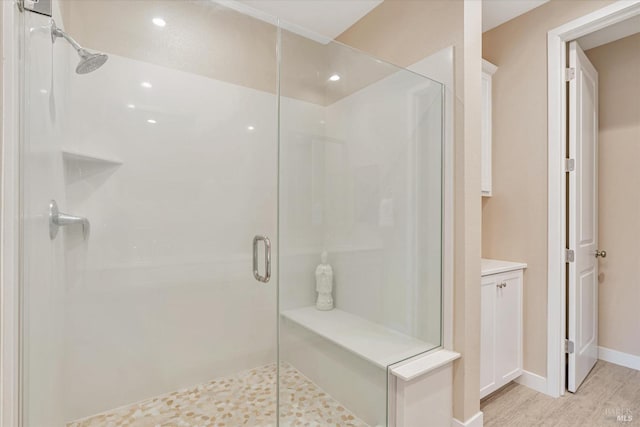 full bathroom with baseboards, wood finished floors, and a shower stall