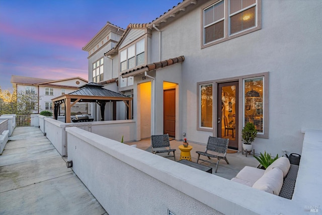 rear view of house featuring outdoor lounge area, a gazebo, stucco siding, and a tile roof
