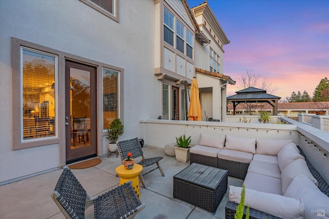 patio terrace at dusk with outdoor lounge area and a gazebo