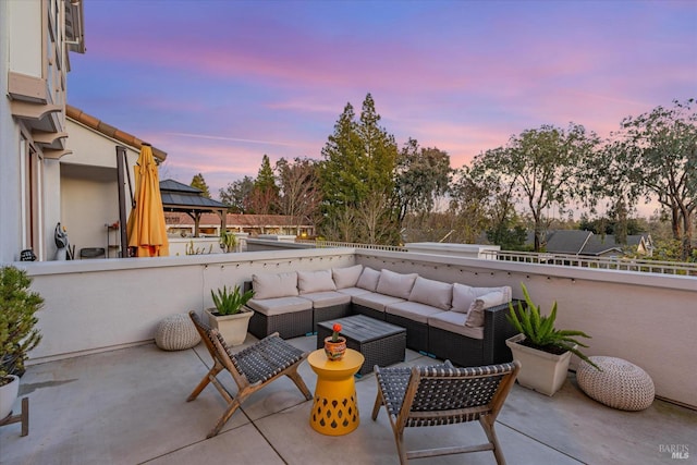patio terrace at dusk featuring a gazebo and an outdoor living space