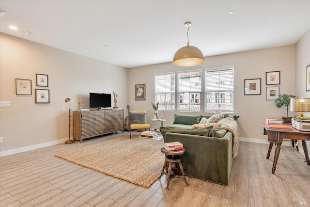 living area with baseboards, recessed lighting, and light wood-type flooring