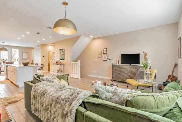 living area with light wood-style flooring, visible vents, and recessed lighting