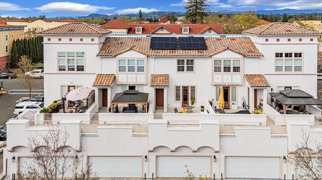 view of front facade featuring a residential view, a tile roof, a garage, and solar panels