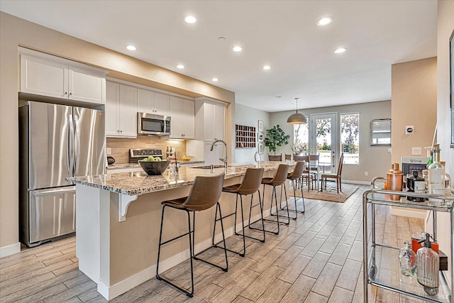 kitchen featuring decorative backsplash, a kitchen bar, wood tiled floor, and stainless steel appliances