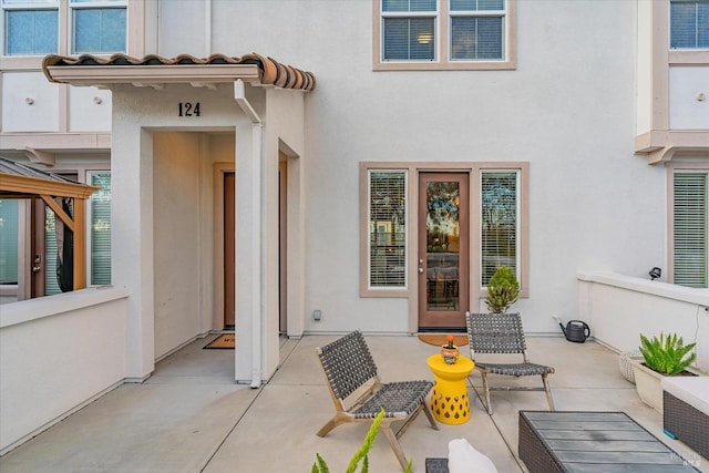 view of exterior entry featuring stucco siding and a patio area