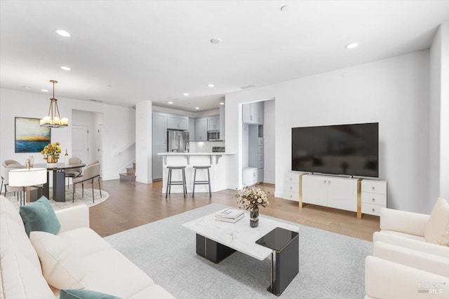 living area with an inviting chandelier, stairway, recessed lighting, and light wood-style floors