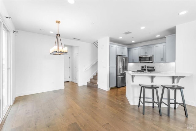 kitchen with visible vents, a peninsula, appliances with stainless steel finishes, a breakfast bar area, and light countertops