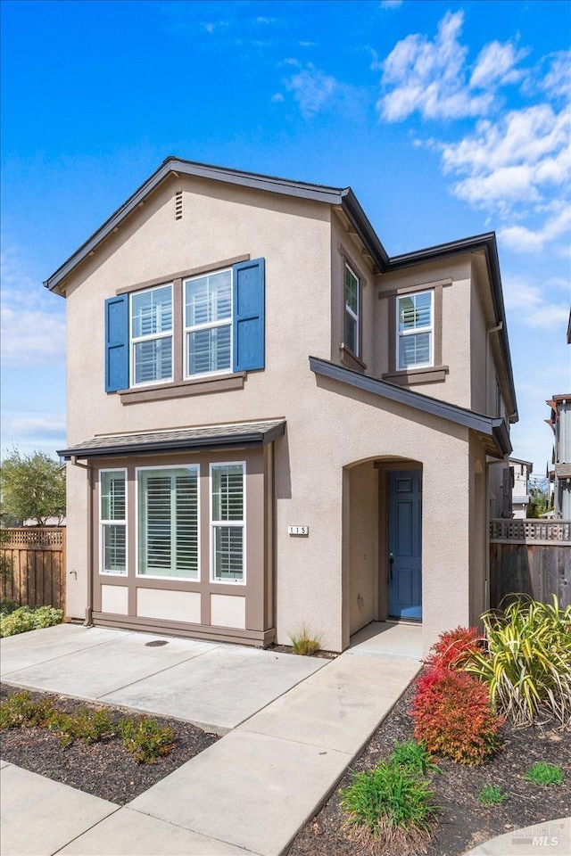 traditional-style home featuring a patio area, fence, and stucco siding