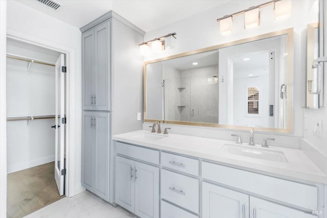 bathroom featuring a shower stall, a spacious closet, marble finish floor, and a sink