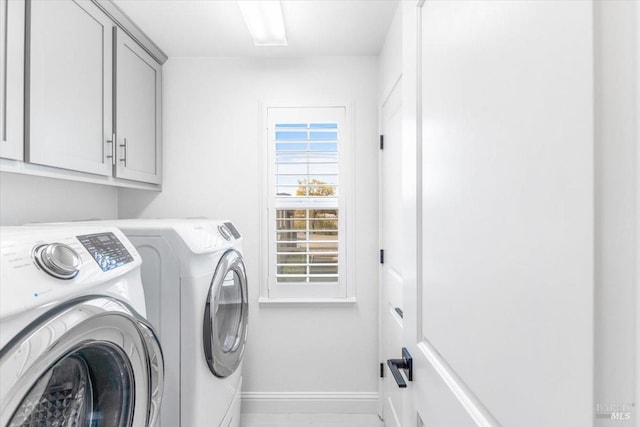 clothes washing area featuring washer and dryer, cabinet space, and baseboards