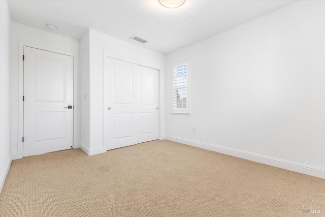 unfurnished bedroom with visible vents, light carpet, baseboards, and a closet