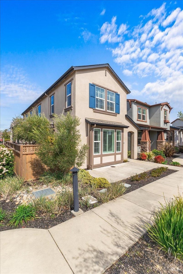 view of front of property featuring a patio area, fence, and stucco siding