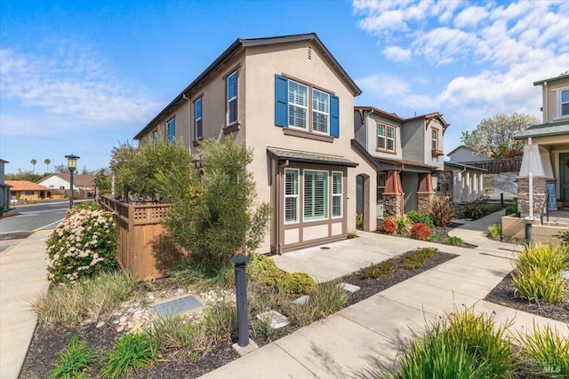 view of front of home with a residential view, stucco siding, and fence