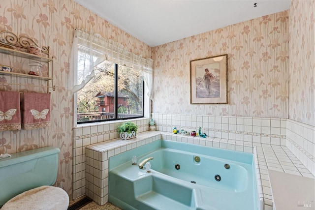 bathroom with a tub with jets, a healthy amount of sunlight, and wallpapered walls