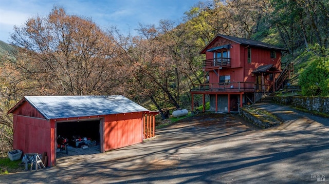 view of outdoor structure with aphalt driveway, an outbuilding, and a forest view