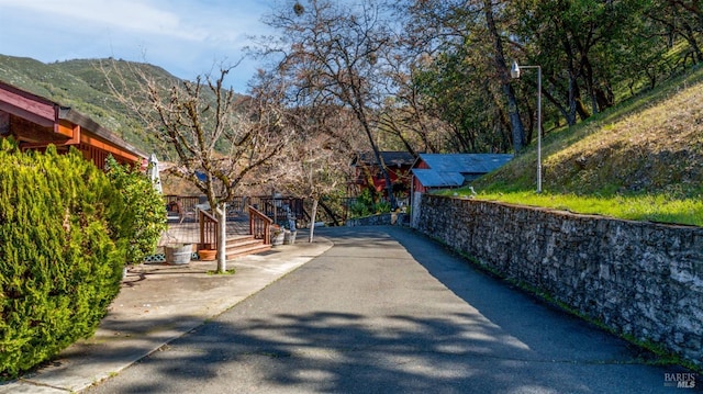 view of street with aphalt driveway and a mountain view