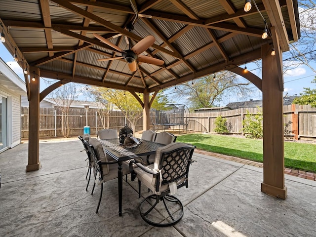 view of patio / terrace with outdoor dining space, a gazebo, a trampoline, and a fenced backyard