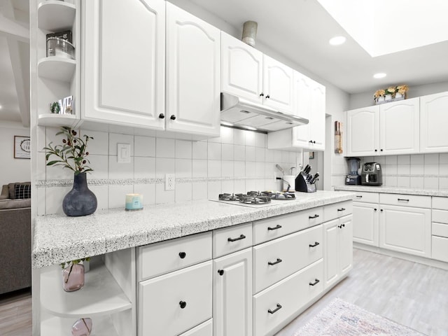 kitchen featuring under cabinet range hood, white cabinets, white gas stovetop, and open shelves