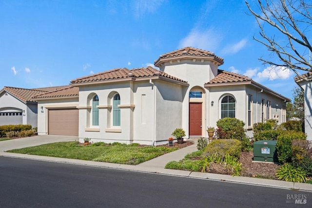 mediterranean / spanish house with stucco siding, driveway, an attached garage, and a tile roof