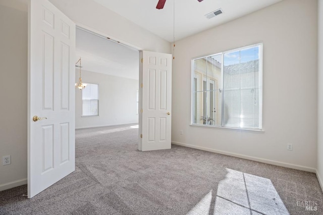 spare room with carpet flooring, baseboards, a ceiling fan, and visible vents