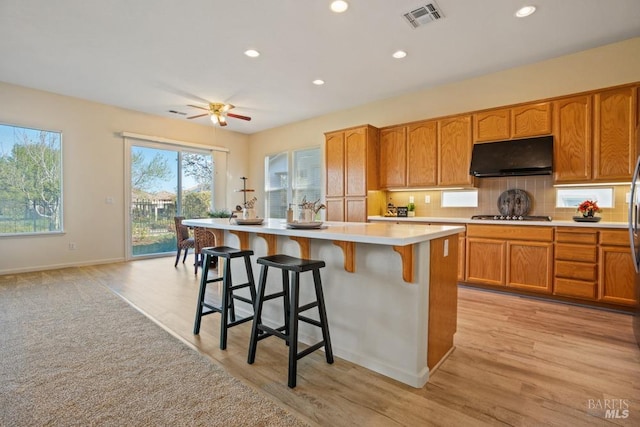 kitchen with visible vents, stainless steel gas cooktop, under cabinet range hood, light countertops, and baseboards