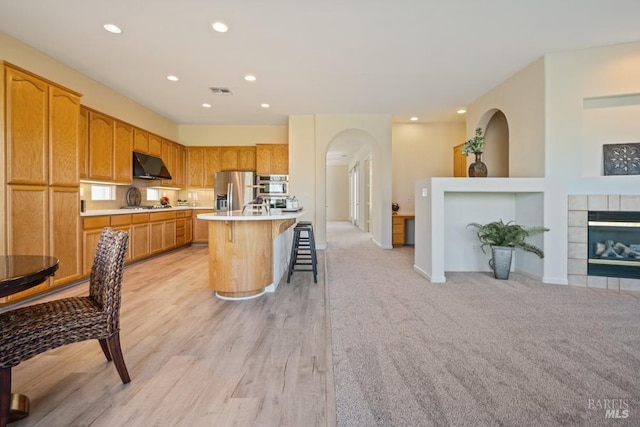 kitchen featuring under cabinet range hood, recessed lighting, appliances with stainless steel finishes, and a breakfast bar