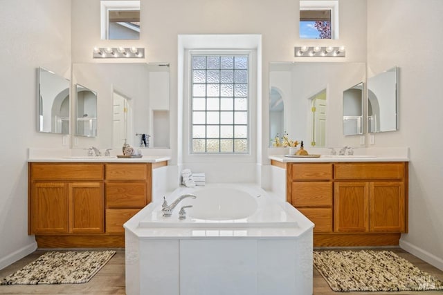 bathroom with a bath, two vanities, and a sink