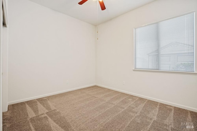 empty room with ceiling fan, baseboards, and carpet