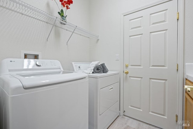 laundry area with independent washer and dryer, laundry area, and light wood-type flooring