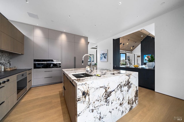 kitchen featuring a center island with sink, modern cabinets, oven, and a sink