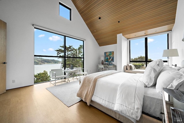 bedroom with wooden ceiling, wood finished floors, a water view, and a towering ceiling