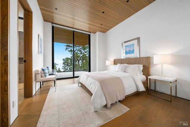 bedroom featuring wooden ceiling, wood finished floors, and expansive windows