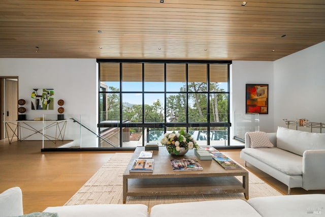 living area featuring a wall of windows, a wealth of natural light, wood ceiling, and wood finished floors