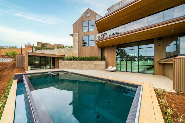 view of swimming pool with a patio, fence, and a pool with connected hot tub