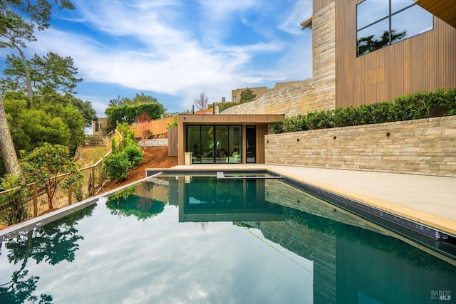 outdoor pool featuring an exterior structure, a patio area, an outbuilding, and fence