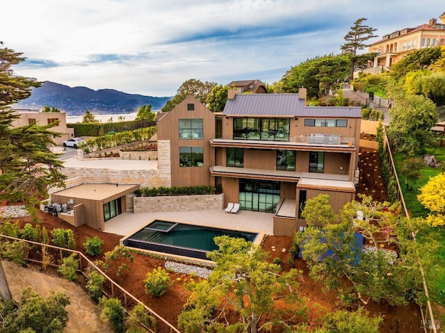 rear view of property featuring a standing seam roof, a patio, a mountain view, metal roof, and a balcony