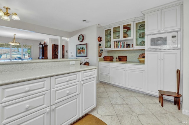 kitchen with white microwave, visible vents, light countertops, and light tile patterned floors