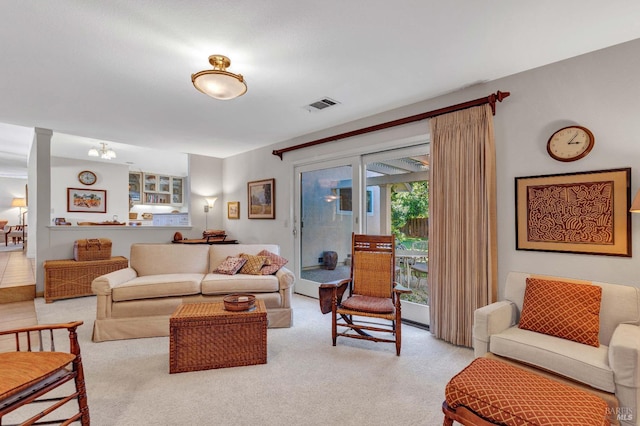 living room with decorative columns, visible vents, and light carpet