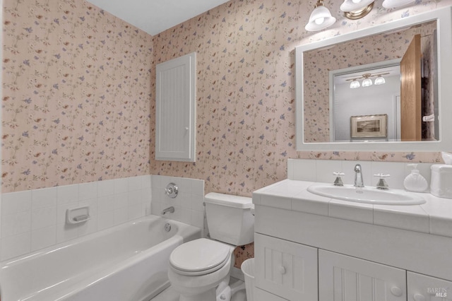 full bathroom with vanity, a garden tub, toilet, and wallpapered walls