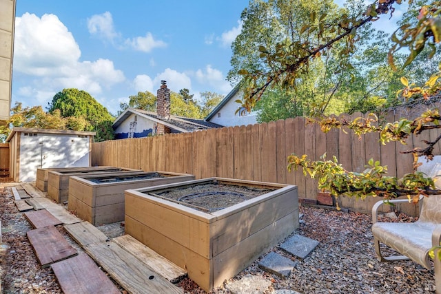 view of patio featuring a storage shed, fence, an outdoor structure, and a garden