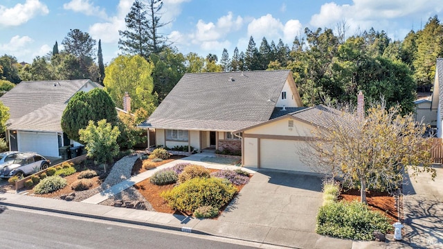 view of front facade featuring concrete driveway, a chimney, a garage, and stucco siding