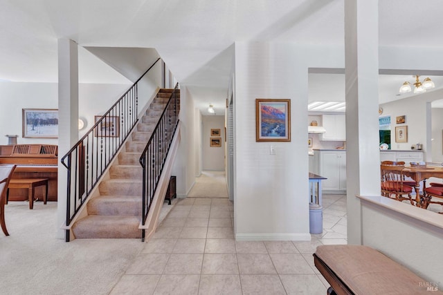 staircase with tile patterned floors, baseboards, and an inviting chandelier