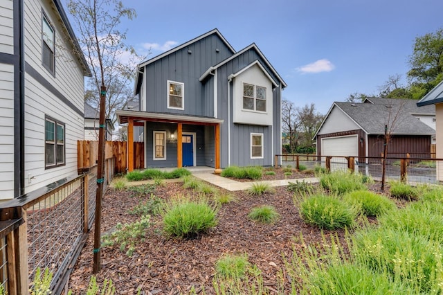 view of front of home featuring an outbuilding, fence, covered porch, board and batten siding, and a garage