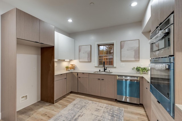 kitchen featuring light wood-style flooring, recessed lighting, a sink, light countertops, and appliances with stainless steel finishes