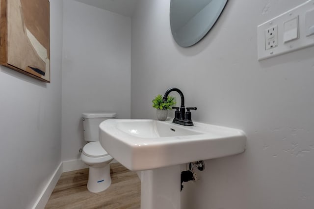 bathroom featuring toilet, baseboards, and wood finished floors