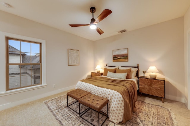 bedroom featuring visible vents, light colored carpet, baseboards, and ceiling fan