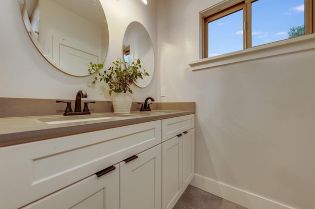 bathroom with double vanity, baseboards, and a sink