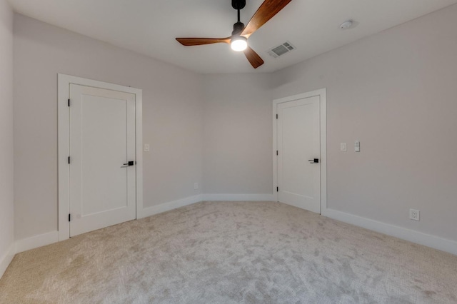 unfurnished room with visible vents, carpet floors, baseboards, and ceiling fan