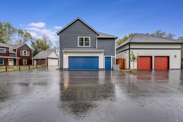 view of front of property featuring board and batten siding, fence, cooling unit, an outdoor structure, and a garage