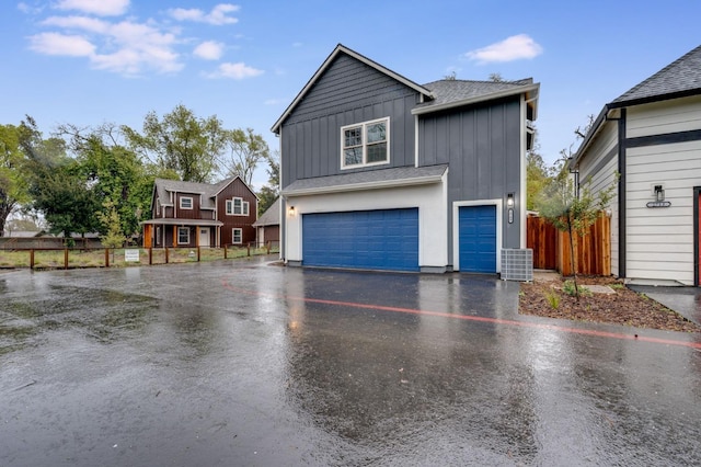 view of front facade with board and batten siding, a shingled roof, fence, driveway, and an attached garage